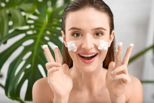 Hermosa joven aplicación de crema facial en casa — Foto de Stock