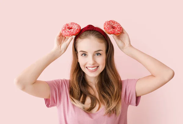 Забавная девушка с вкусными пончиками на цветном фоне — стоковое фото