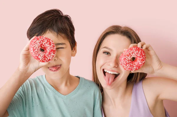 Cute mother and little son with tasty donuts on color background — Stock Photo, Image