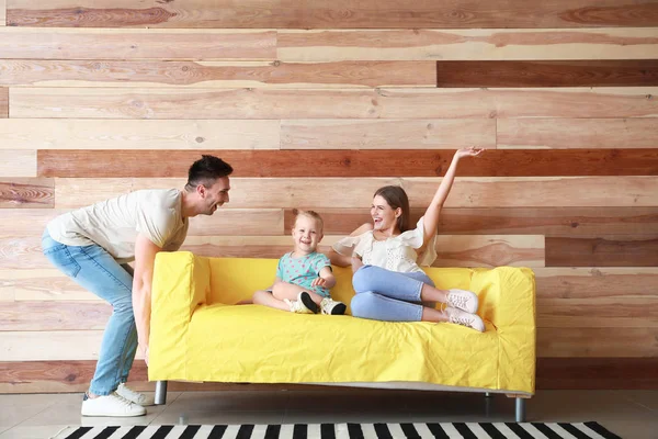Joven tratando de mover el sofá con la esposa sentada y la hija —  Fotos de Stock