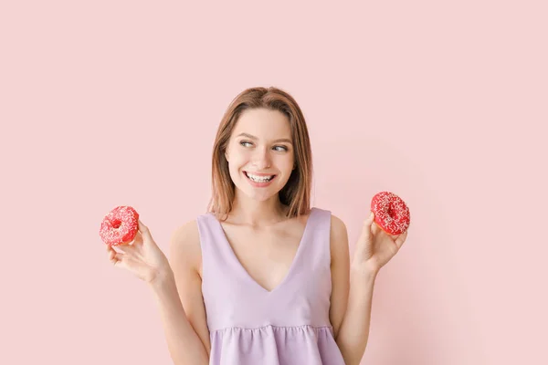 Funny young woman with tasty donuts on color background — Stock Photo, Image