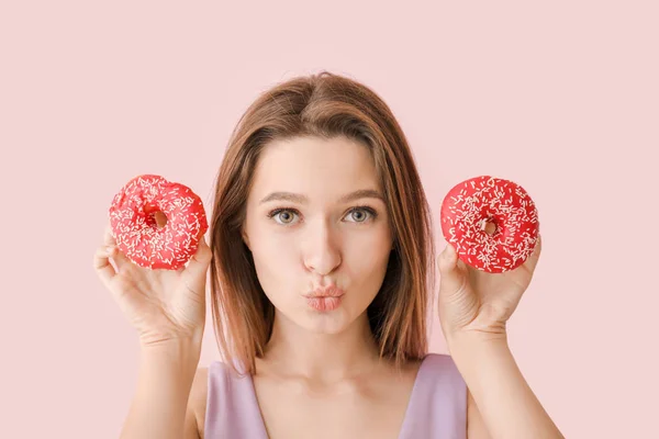 滑稽的年轻女人，与美味甜甜圈上颜色背景 — 图库照片