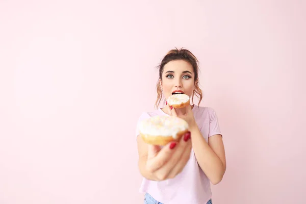 Mooie jonge vrouw met donuts op kleur achtergrond — Stockfoto