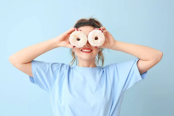Funny young woman with donuts on color background — Stock Photo, Image