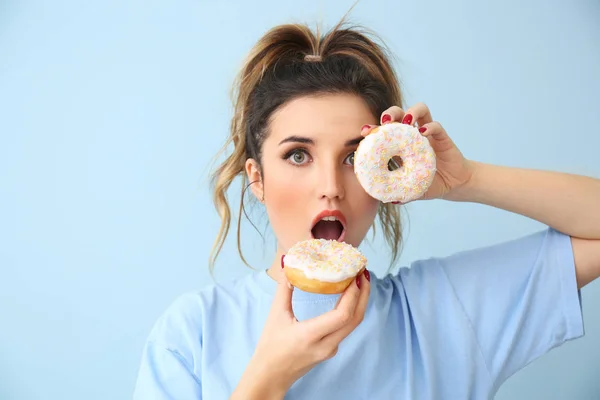 Surpreendida jovem com donuts em fundo de cor — Fotografia de Stock