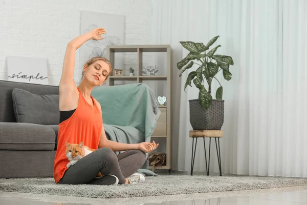 Giovane donna con gatto carino praticare yoga a casa — Foto Stock