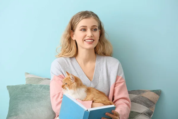 Bella giovane donna con carino gatto lettura libro a casa — Foto Stock