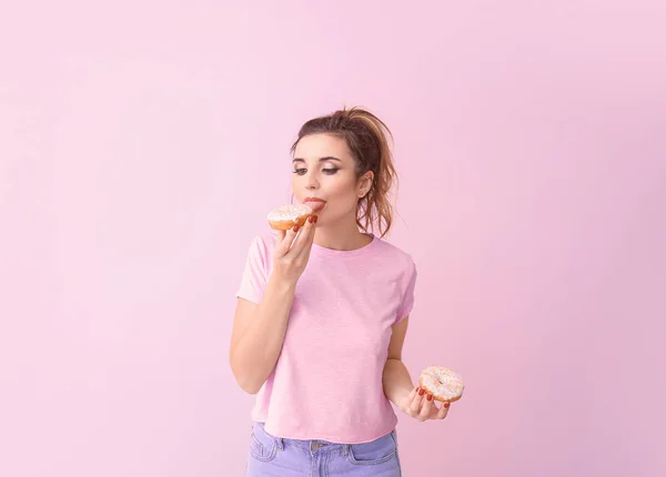 Belle jeune femme avec des beignets sur fond de couleur — Photo