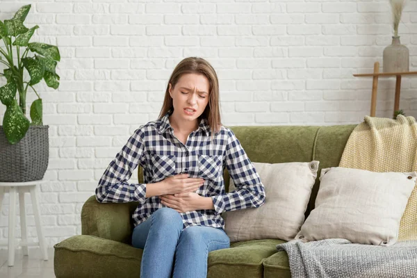 Mujer joven que sufre de dolor abdominal en casa — Foto de Stock