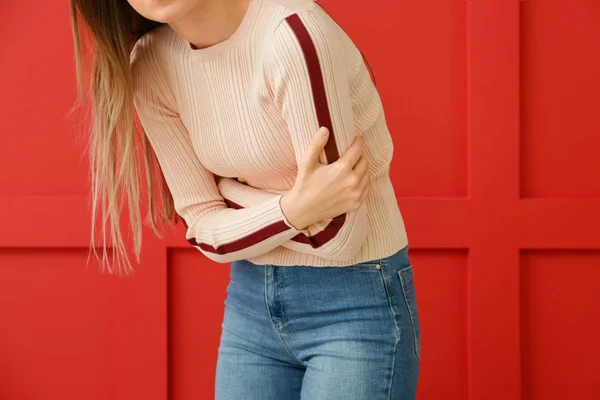 Jeune femme souffrant de douleurs abdominales sur fond de couleur — Photo