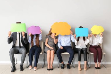 Işık duvarının yanında boş konuşma baloncukları olan bir grup iş adamı