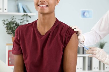 Klinikte genç bir çocuğu aşılayan doktor.