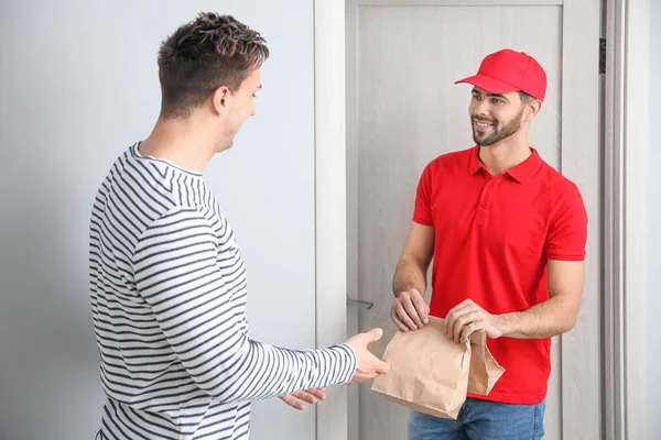 Man receiving order from courier of food delivery company — Stock Photo, Image