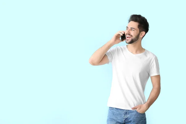 Happy jongeman praten door mobiele telefoon op kleur achtergrond — Stockfoto