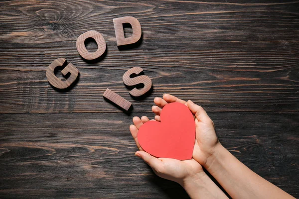 Kobieta ręce i tekst Bóg jest miłość na drewnianym tle — Zdjęcie stockowe