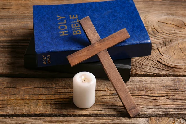 Christian cross, Bibles and candle on wooden background