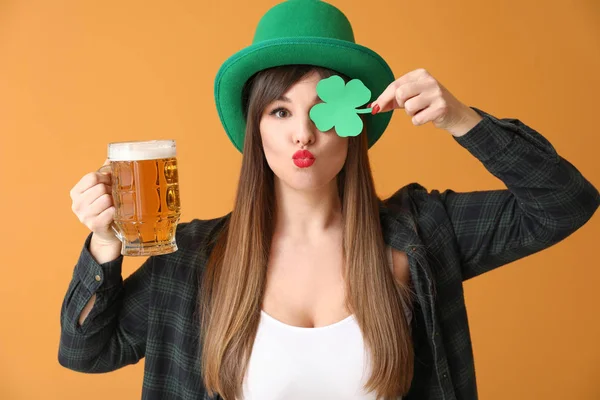 Grappige jonge vrouw met papieren klaver en bier op kleur achtergrond. St. Patrick 's Day viering — Stockfoto