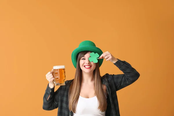 Grappige jonge vrouw met papieren klaver en bier op kleur achtergrond. St. Patrick 's Day viering — Stockfoto