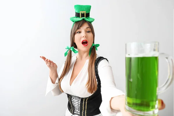 Zabawna młoda kobieta z piwem na jasnym tle. Święto św. Patryka — Zdjęcie stockowe
