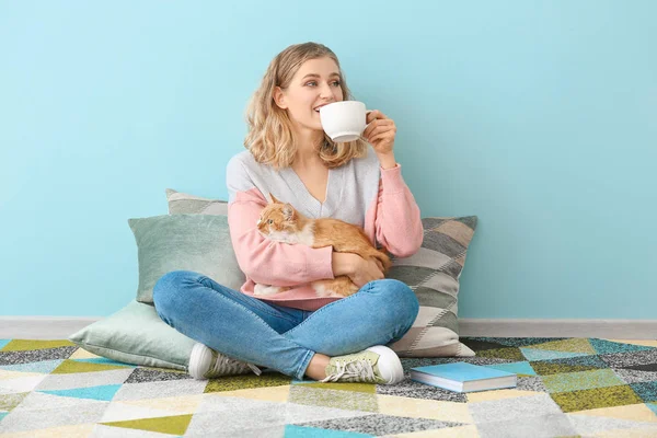 Bella giovane donna con gatto carino bere il tè a casa — Foto Stock