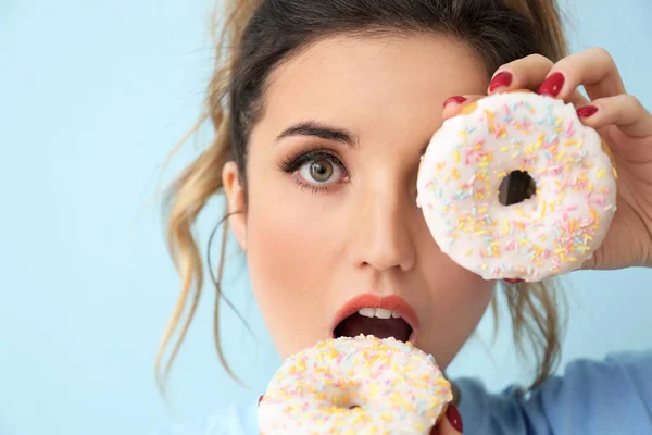 Surpreendida jovem com donuts em fundo de cor — Fotografia de Stock