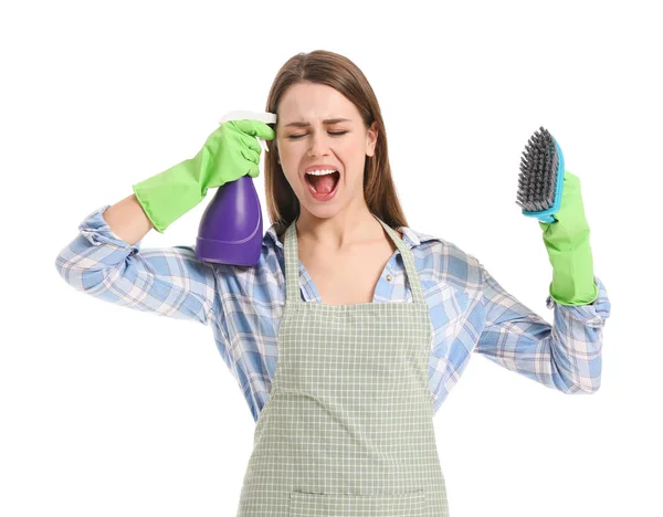 Stressed young housewife with cleaning supplies on white background