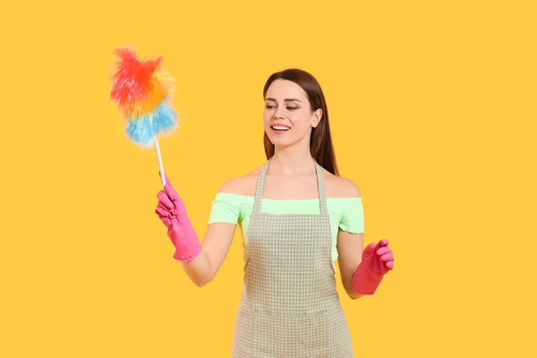 Young housewife with dust brush on color background — Stock Photo, Image