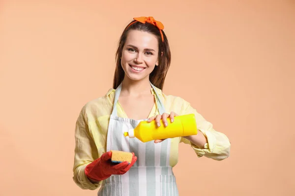 Young housewife with cleaning supplies on color background — 스톡 사진