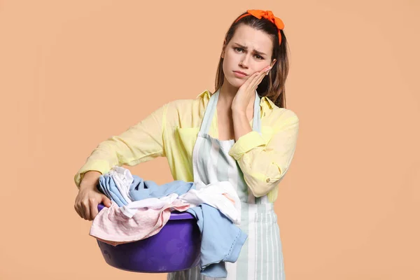 Cansado jovem dona de casa com lavanderia no fundo de cor — Fotografia de Stock