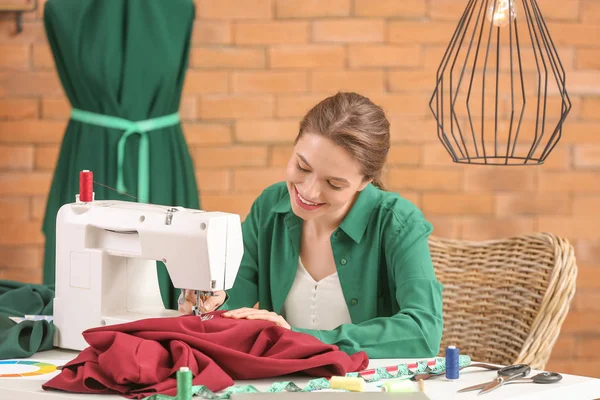 Jonge vrouw naait kleding in atelier — Stockfoto