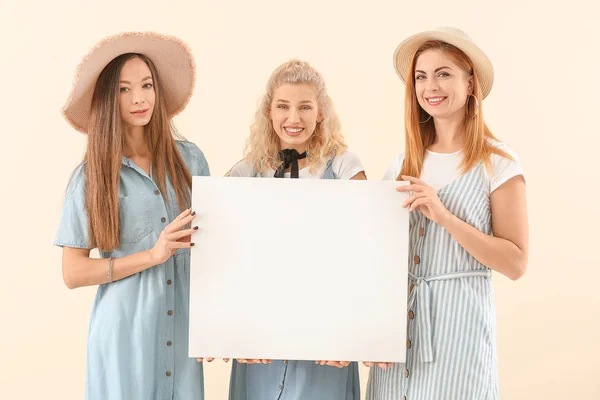 Beautiful young women with blank poster on color background — Stock Photo, Image