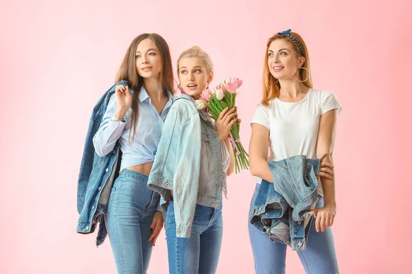 Vackra unga kvinnor med blommor på färg bakgrund. Internationella kvinnodagen firas — Stockfoto
