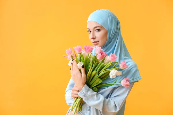 Gyönyörű muszlim nő virágokkal színes háttéren. Nemzetközi nőnapi ünneplés — Stock Fotó