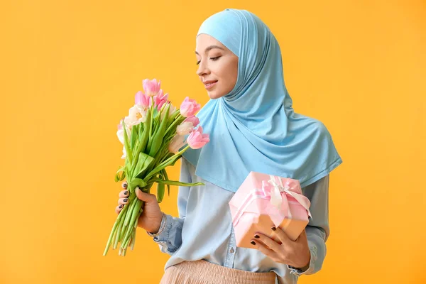美丽的穆斯林女人，有花朵和彩色背景的礼物。二.国际妇女节庆祝活动 — 图库照片