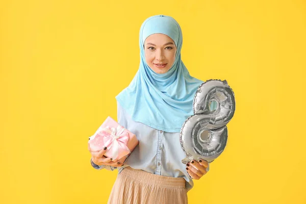 Mulher muçulmana bonita com balão em forma de figura 8 e presente no fundo de cor. Celebração do Dia Internacional da Mulher — Fotografia de Stock