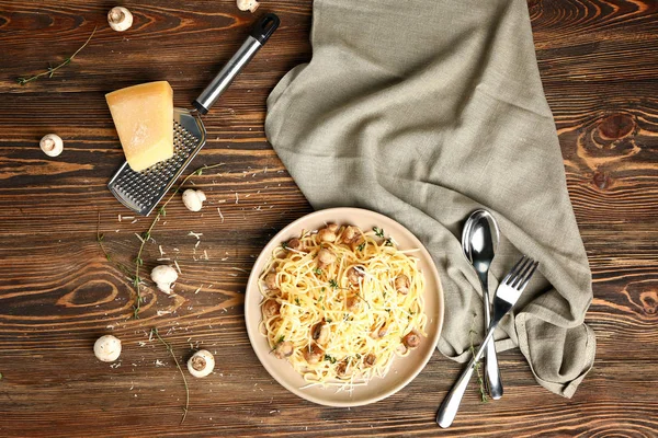 Plate with tasty pasta and mushrooms on wooden table — Stock Photo, Image