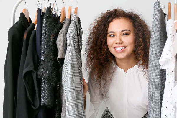 Estilista afro-americano perto de rack com roupas modernas — Fotografia de Stock