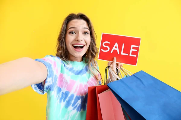 Žena stylistka s nákupními taškami s selfie na barevném pozadí — Stock fotografie