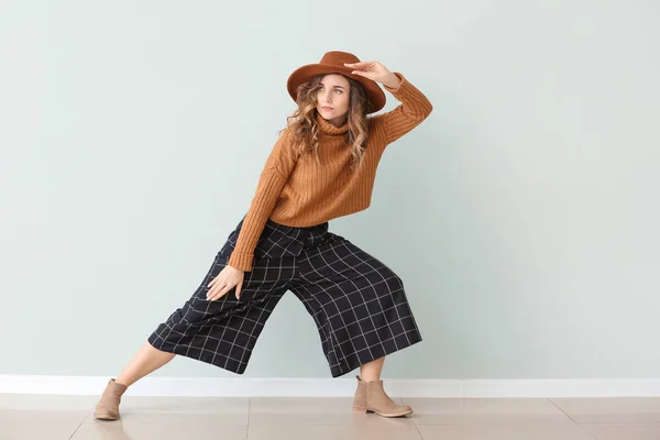 Beautiful young woman in warm sweater near light wall — 스톡 사진