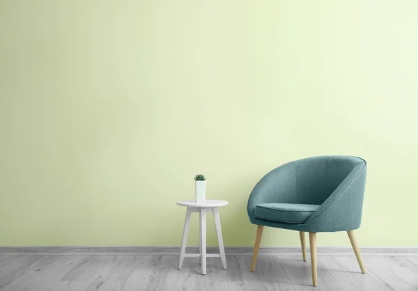 Stylish armchair with table near color wall in room — Stock Photo, Image