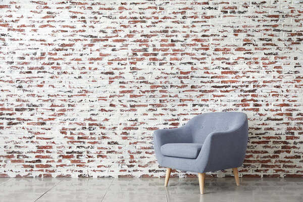 Stylish armchair near brick wall in room