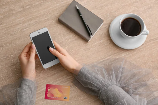 Woman using mobile phone for online banking at table — Stock Photo, Image