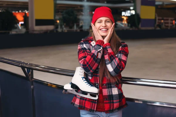 Young woman with ice skates near rink — Stock Photo, Image