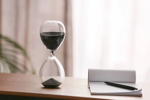 Hourglass with notebook on table in office. Time management concept — Stock Photo, Image