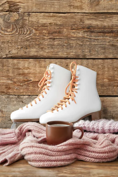 Ice skate shoes with clothes and cup of coffee on wooden background — Stock Photo, Image