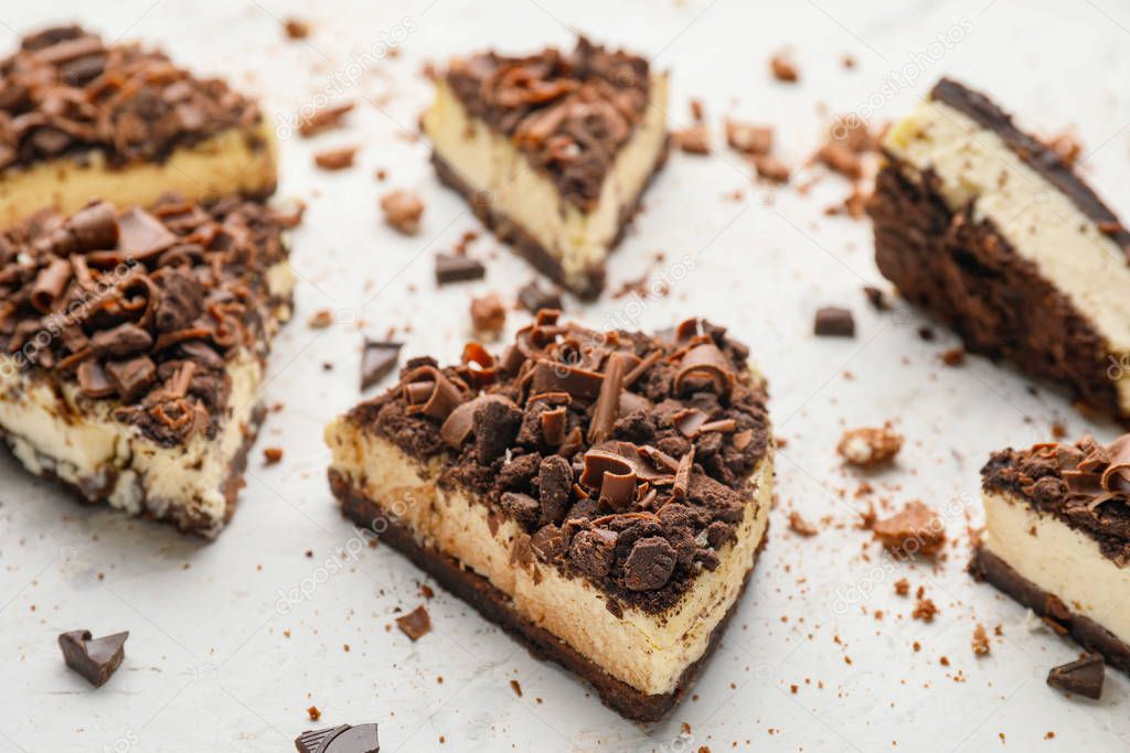 Pieces of tasty chocolate cheesecake on light background