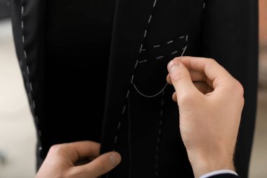 Young tailor working with mannequin in atelier, closeup