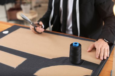 Young tailor working at table in atelier, closeup