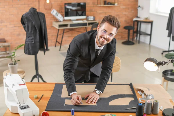 Young tailor working at table in atelier — Stockfoto