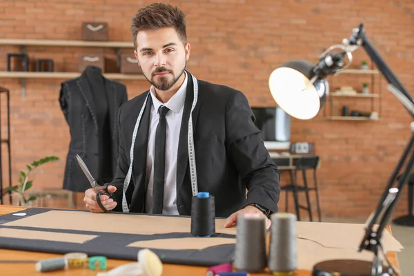 Jeune tailleur travaillant à table en atelier — Photo